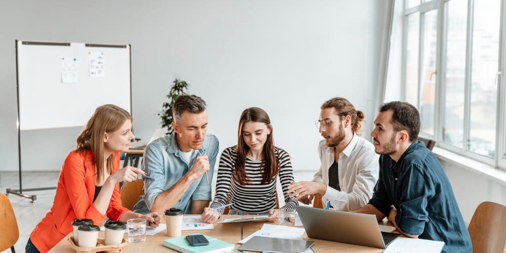 5 mensen werken in een team en overleggen.